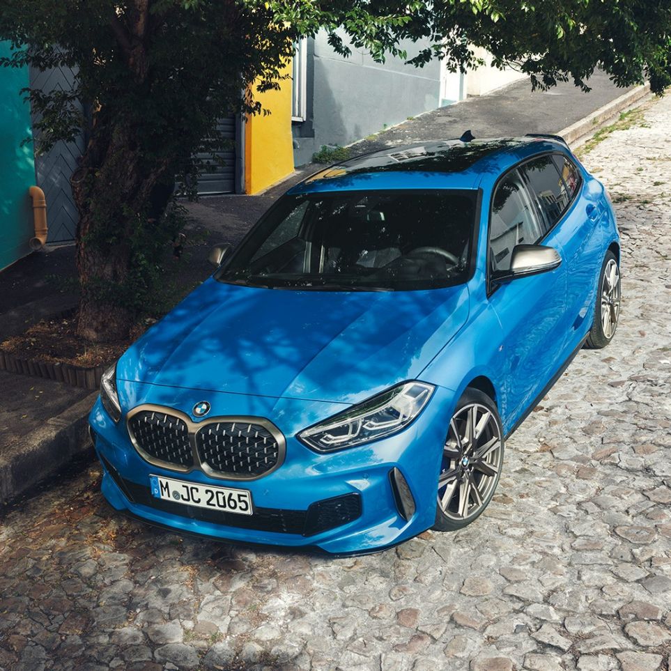 BMW Serie 1 a un costado del camino. BMW Serie 1 en Misano Blue metálico, vista frontal tres cuartos, estacionado a un costado del camino desde una vista de toma aérea.