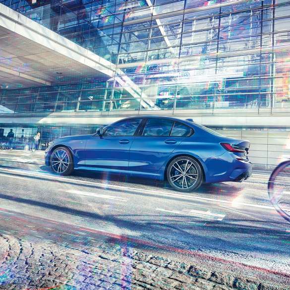 BMW Serie 3, vista del lateral Imagen del lateral de la Sedán deportiva BMW Serie 3 de día delante de un edificio de cristal.