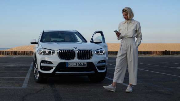 My BMW App BMW Modelo femenina con smartphone delante de BMW My BMW App BMW Modelo femenina con smartphone delante de BMW