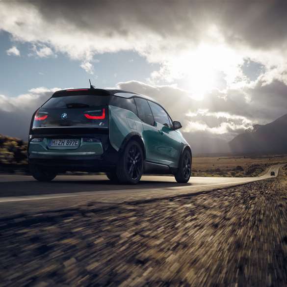 BMW i3 2018 Vista de tres cuartos de la zaga, en marcha por una carretera secundaria BMW i3 I01 2018 Jucarobeige con detalles Frozen Grey metalizado, vista de tres cuartos de la zaga, en marcha por una carretera secundaria