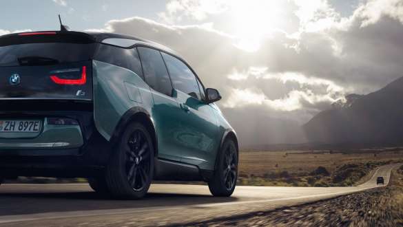 BMW i3 2018 Vista de tres cuartos de la zaga, en marcha por una carretera secundaria BMW i3 I01 2018 Jucarobeige con detalles Frozen Grey metalizado, vista de tres cuartos de la zaga, en marcha por una carretera secundaria