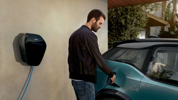 BMW i3 2018 en un punto de carga público, Jucarobeige con detalles Frozen Grey metalizado Pareja cargando su BMW i3 en un punto de carga público I01 2018 Jucarobeige con detalles Frozen Grey metalizado