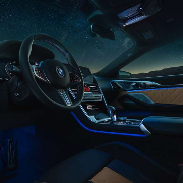BMW M8 Competition Coupé, cabina. BMW M8 Competition Coupé, cabina de noche con volante de cuero M y luz ambiente azul.