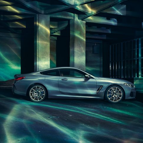 BMW M850i xDrive Coupé, vista lateral. BMW M850i xDrive Coupé en Barcelona Blue metálico, vista lateral, parado frente a un edificio.