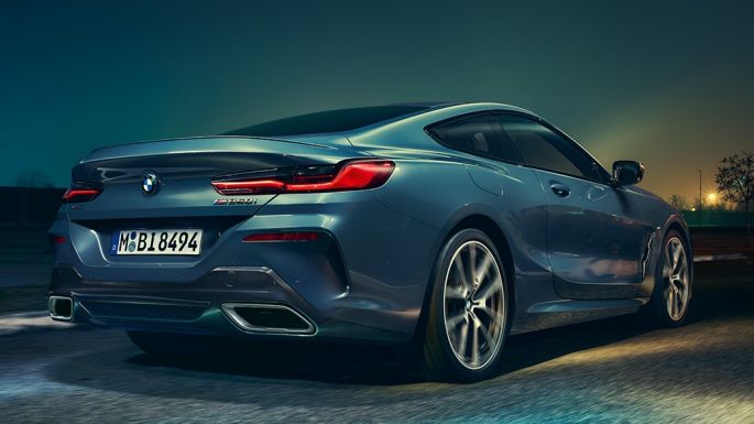 BMW M850i xDrive Coupé, vista trasera. BMW M850i xDrive Coupé en Barcelona Blue metálico, vista trasera, conduciendo de noche.