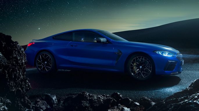 BMW M8 Competition Coupé, vista lateral tres cuartos. BMW M8 Competition Coupé en Marina Bay Blue metálico, vista lateral tres cuartos en alto de noche.