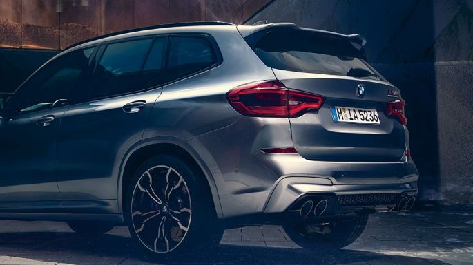 BMW X3 M Competition, vista trasera lateral. BMW X3 M Competition en Donington Grey metálico, exterior, vista trasera lateral con dos personas en primer plano.