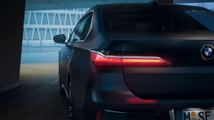 BMW Serie 7 G70 ICE 740i Paquete M Sport, Frozen Deep Grey metalizado, vista de la zaga, con luz trasera roja encendida en el túnel