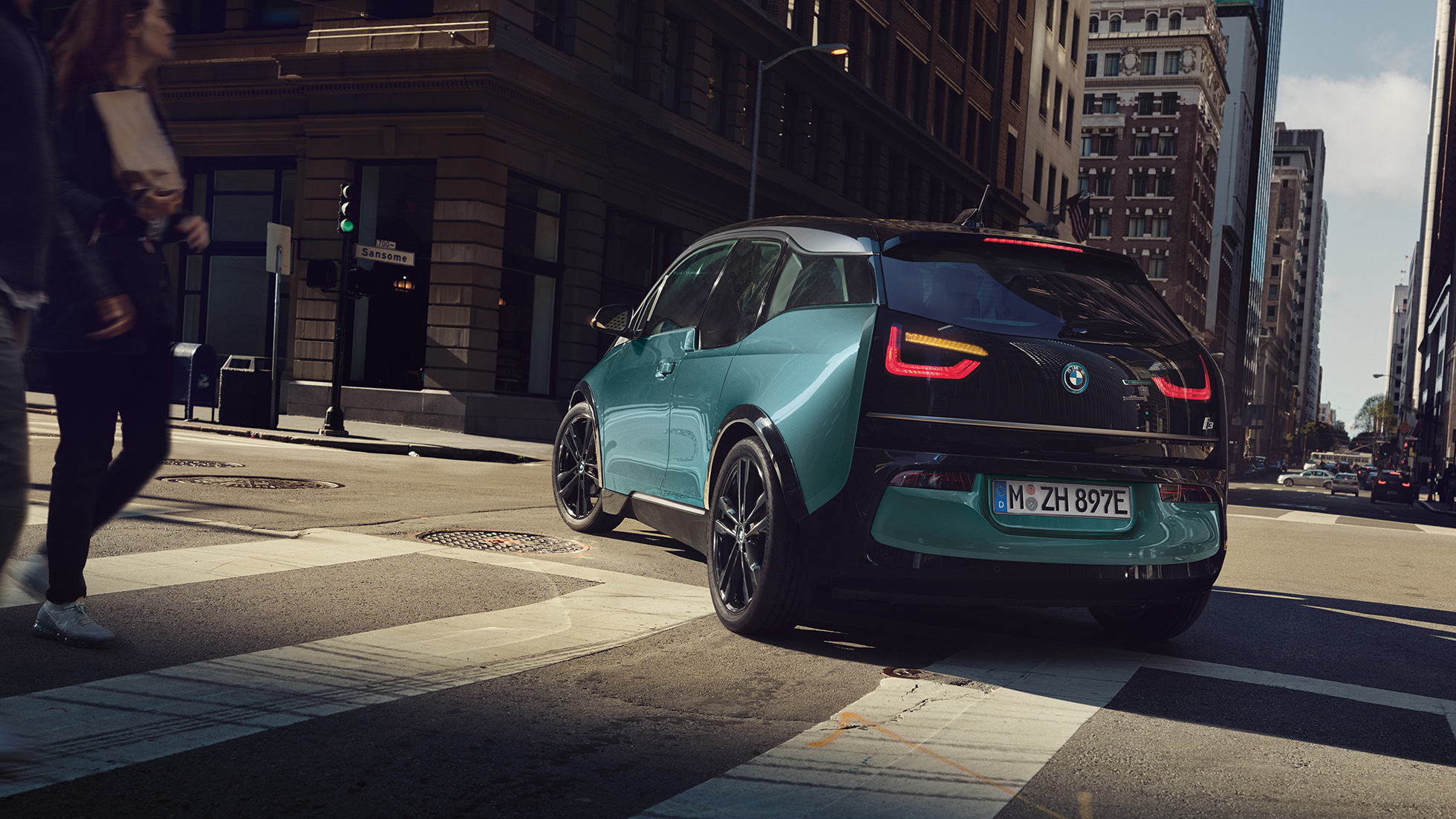 BMW i3 2018 Vista de tres cuartos de la zaga, en marcha BMW i3 I01 2018 Jucarobeige con detalles Frozen Grey metalizado, vista de tres cuartos de la zaga, en marcha en un entorno urbano