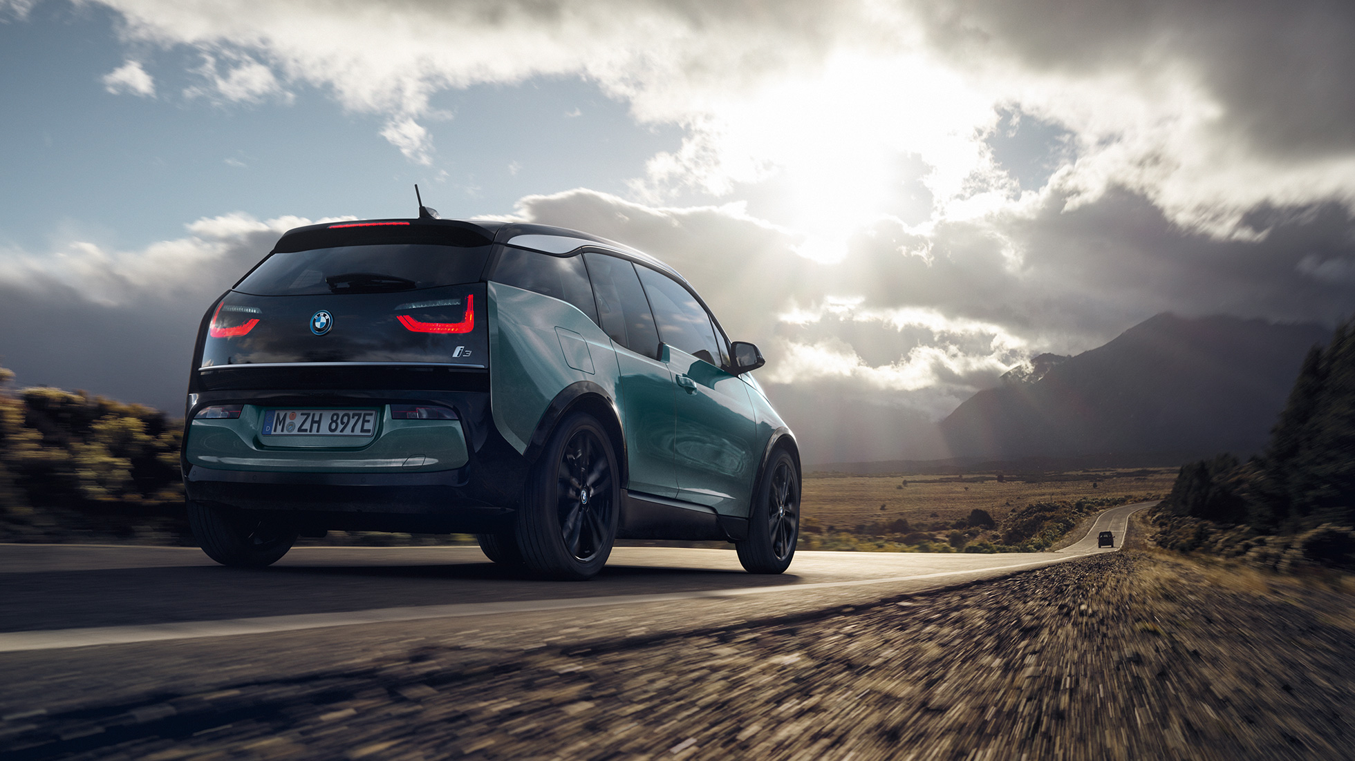 BMW i3 2018 Vista de tres cuartos de la zaga, en marcha por una carretera secundaria BMW i3 I01 2018 Jucarobeige con detalles Frozen Grey metalizado, vista de tres cuartos de la zaga, en marcha por una carretera secundaria