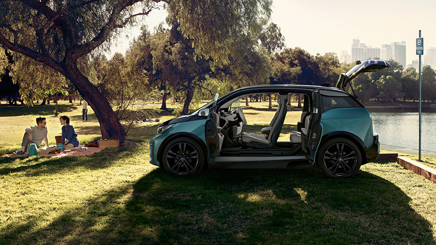BMW i3 2018 en el parque BMW i3 I01 2018 Jucarobeige con detalles Frozen Grey metalizado, vista del lateral, con las puertas abiertas en el parque