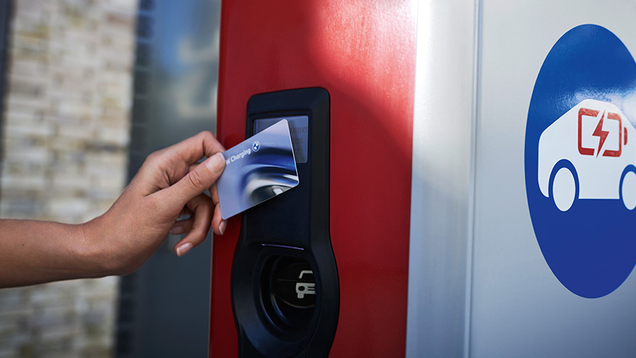 Una persona sostiene una tarjeta BMW Charging en un punto de carga público Una persona sostiene una tarjeta BMW Charging en un punto de carga público