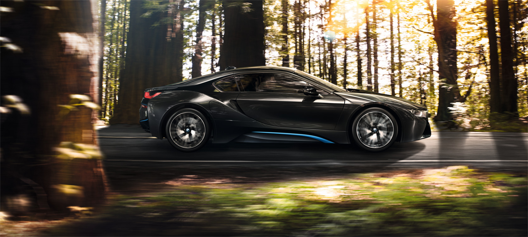 BMW i8 negro: vista lateral derecha, puertas y llantas con árboles al fondo BMW i8 negro: vista lateral derecha, puertas y llantas con árboles al fondo