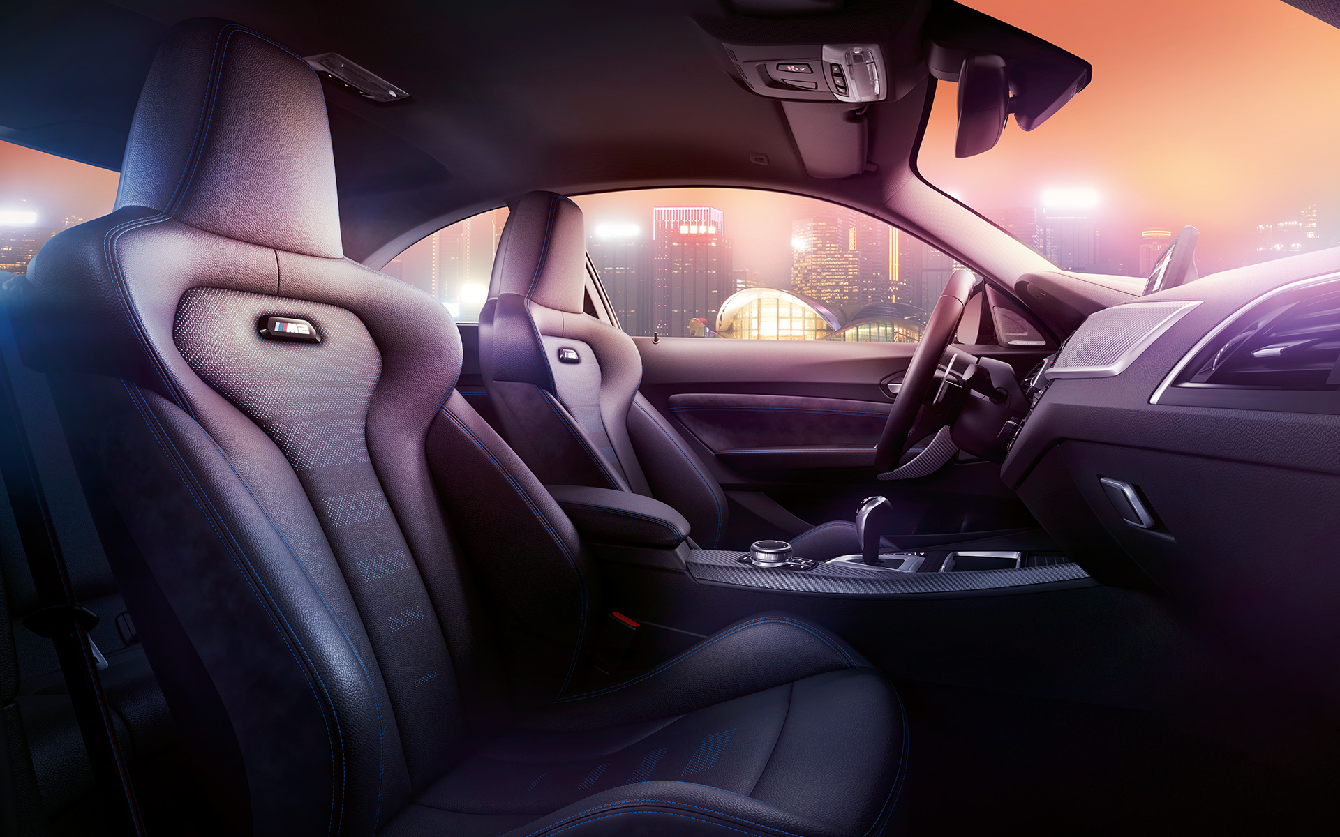 Asientos deportivos del BMW M2 Competition. Cockpit y asientos M Sport del BMW M2 Competition, paisaje nocturno de fondo.