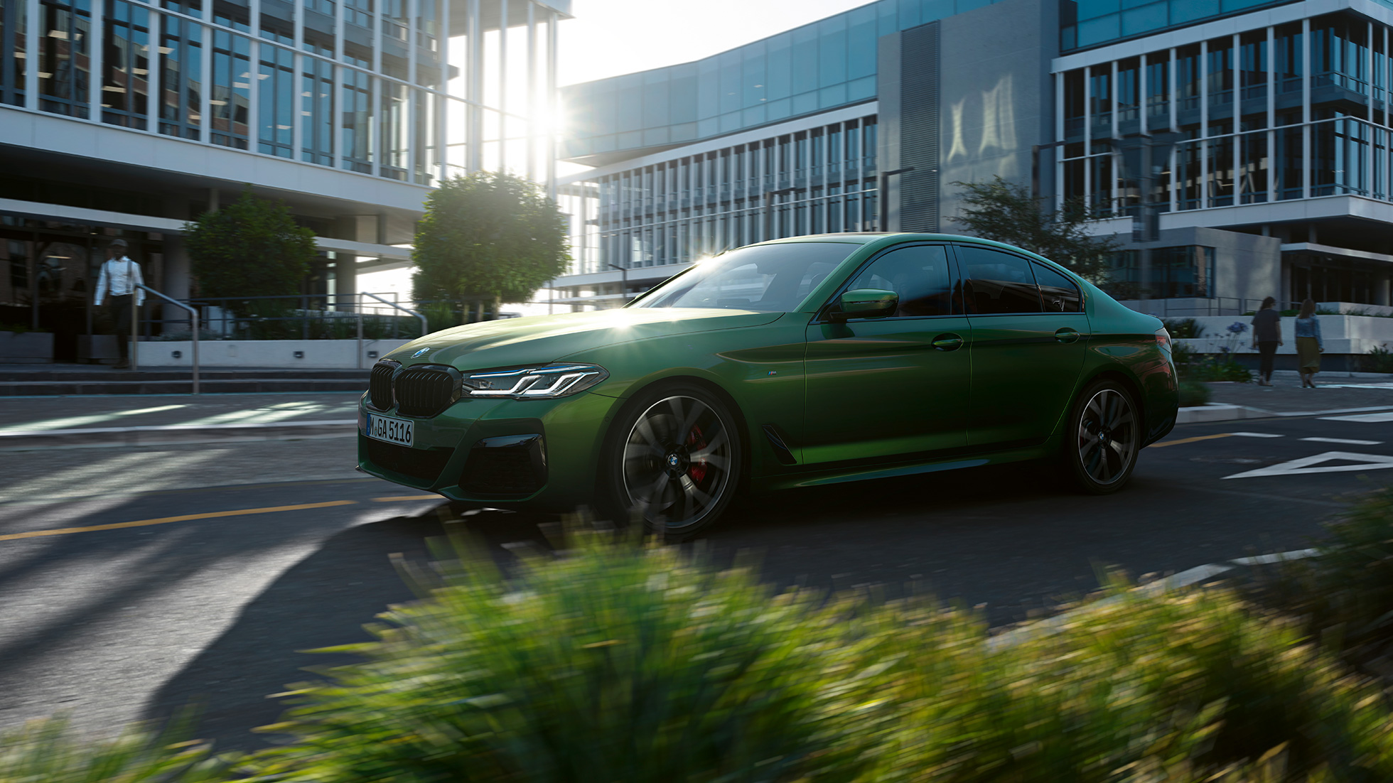 BMW M550i xDrive Sedán G30 LCI Renovación 2020 Vista lateral en marcha BMW M550i xDrive Sedán G30 LCI Renovación 2020 BMW Individual Verde Ermes metalizado Vista lateral en marcha en la ciudad
