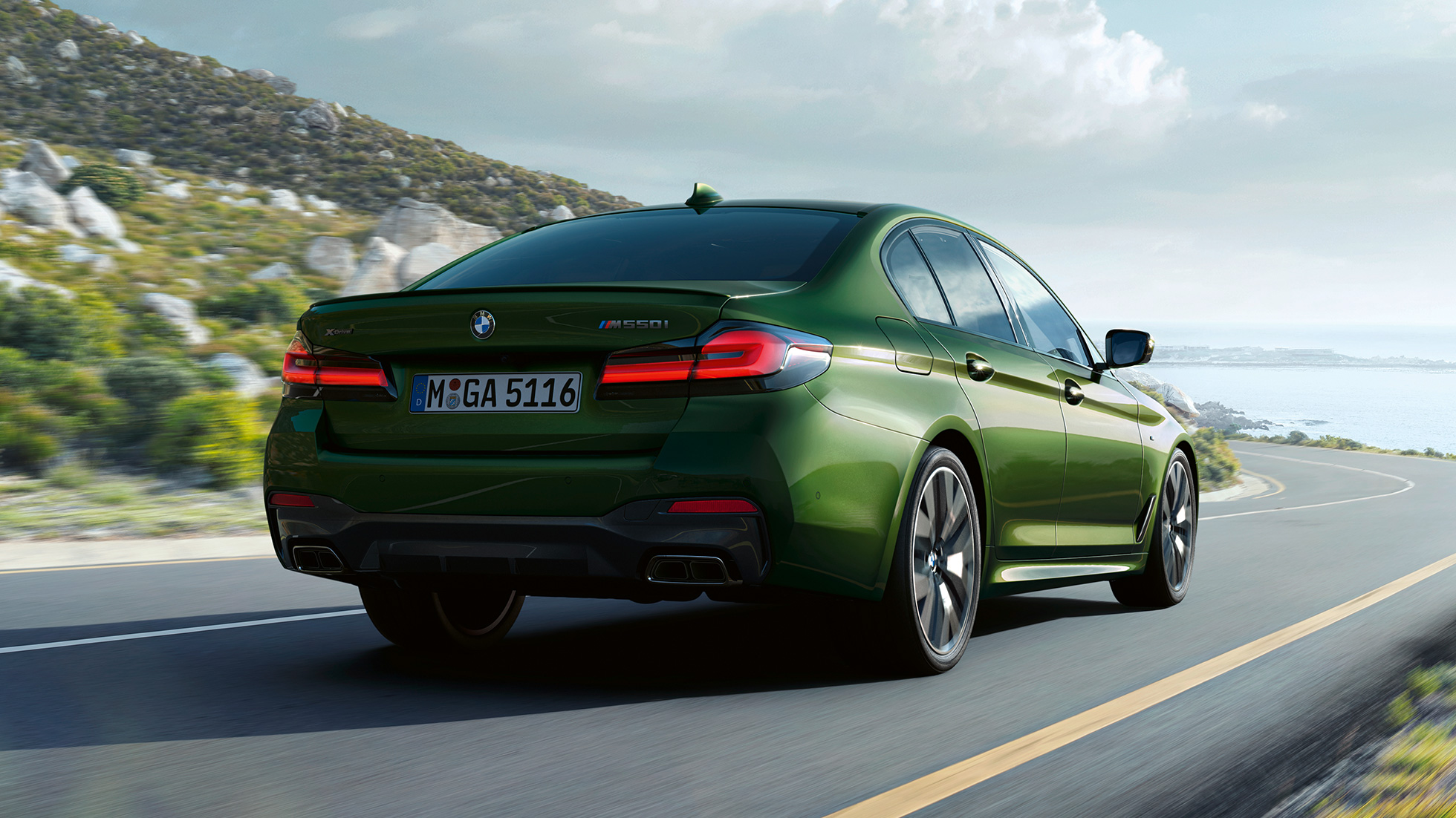 BMW M550i xDrive Sedán G30 LCI Renovación 2020 Vista de la zaga BMW M550i xDrive Sedán G30 LCI Renovación 2020 BMW Individual Verde Ermes metalizado Vista de la zaga en marcha por una carretera
