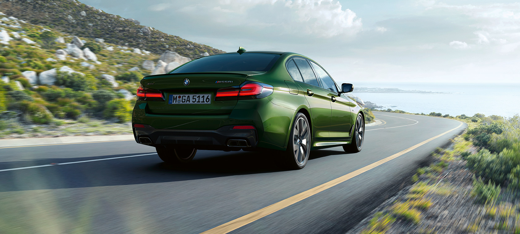 BMW M550i xDrive Sedán G30 LCI Renovación 2020 Vista de tres cuartos de la zaga en marcha BMW M550i xDrive Sedán G30 LCI Renovación 2020 BMW Individual Verde Ermes metalizado Vista de tres cuartos de la zaga en marcha