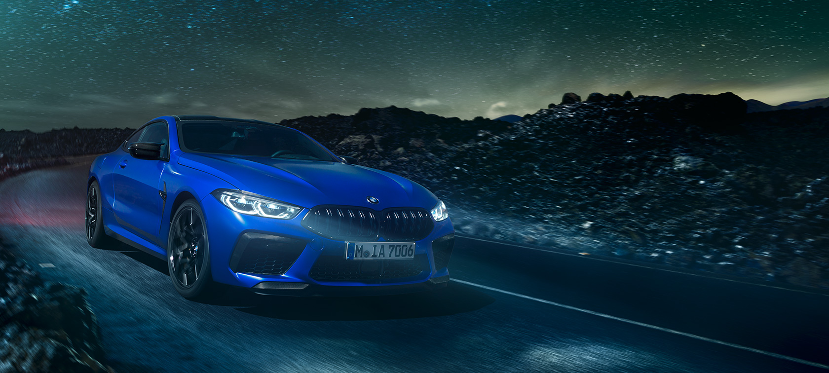 BMW M8 Competition Coupé, vista trasera. BMW M8 Competition Coupé, vista trasera, conduciendo de noche con luna llena.