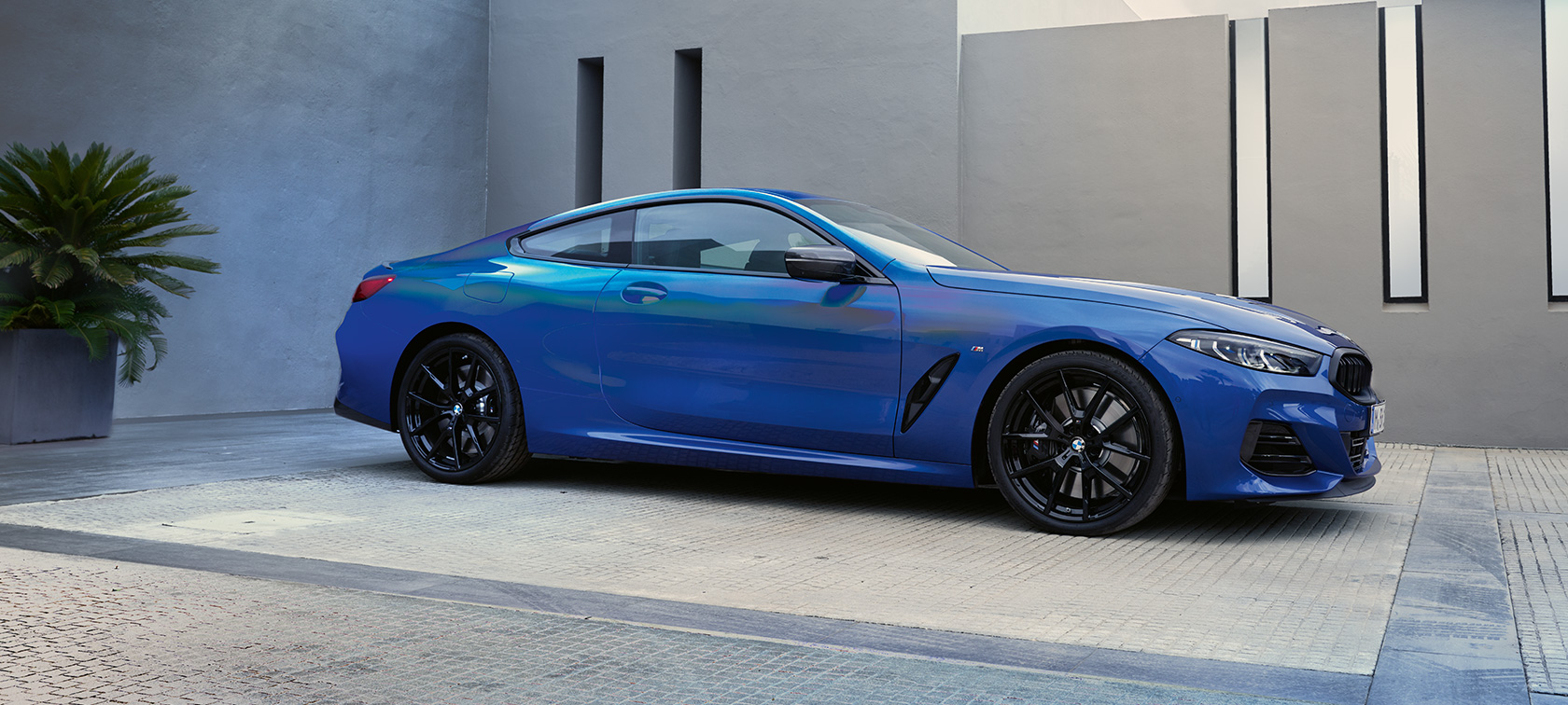 Vista lateral del nuevo BMW M850i xDrive Coupé G15 LCI Renovación 2022 Nuevo BMW M850i xDrive Coupé G15 LCI Renovación 2022 M Portimao Blue metalizado, vista lateral, parado, ante un edificio