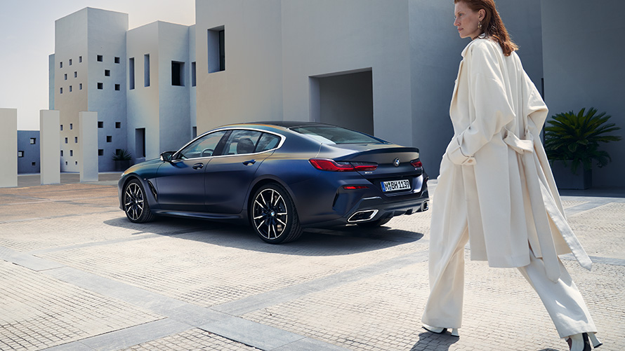 Nuevo BMW M850i xDrive Gran Coupé G16 LCI Renovación 2022 BMW Individual Frozen Tanzanite Blue metalizado, vista de tres cuartos de la zaga, con modelo femenina