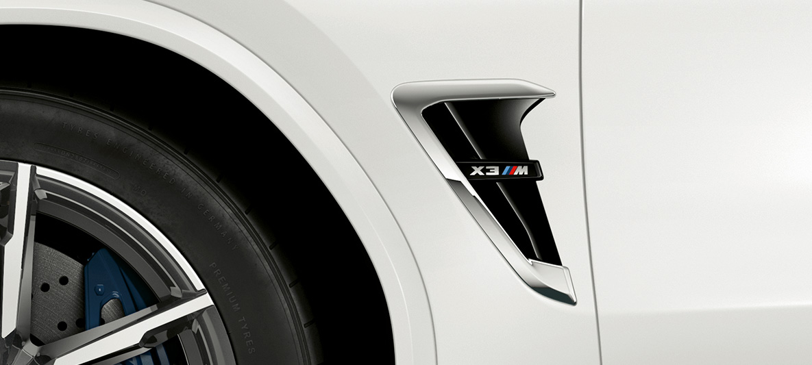 BMW X3 M, láminas M. BMW X3 M en Alpine White, exterior, laminas M con elementos destacados cromados y denominación del modelo.