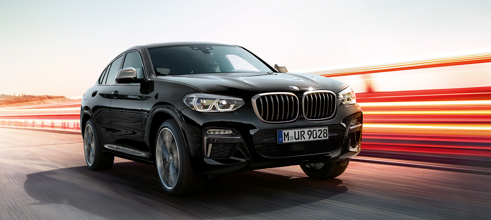 BMW X4 M40i, vista delantera de tres cuartos, lado izquierdo. BMW X4 M40i en Black Sapphire metálico, exterior, vista delantera de tres cuartos, lado izquierdo con franjas claras.