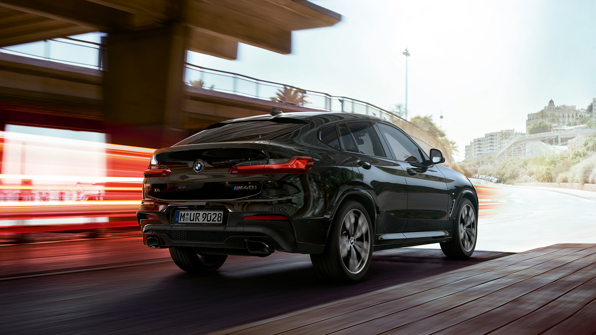 BMW X4 M40i, vista delantera de tres cuartos. BMW X4 M40i en Black Sapphire metálico, conducción, exterior, vista delantera de tres cuartos con franjas claras.
