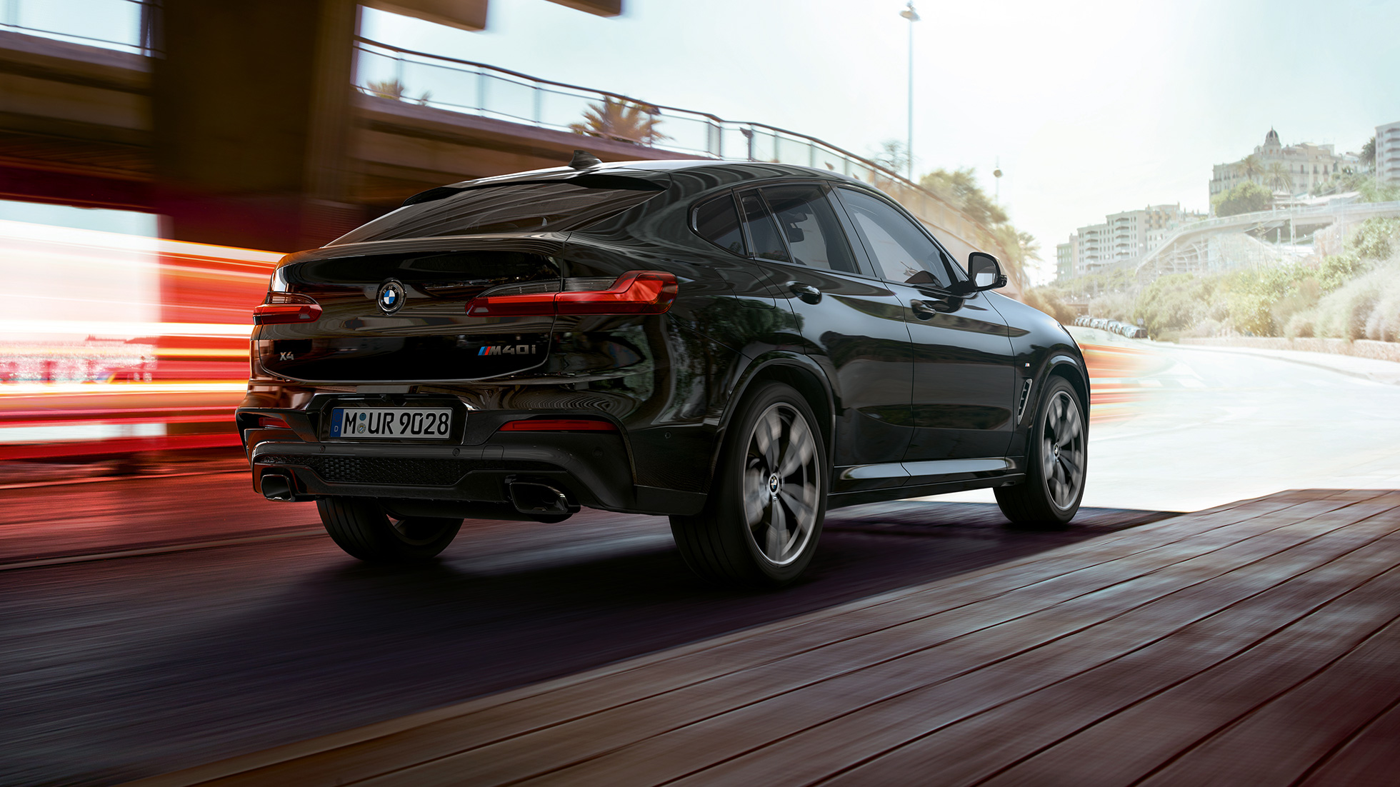 BMW X4 M40i, Vista trasera de tres cuartos. BMW X4 M40i en Black Sapphire metálico, exterior, vista trasera de tres cuartos, lado derecho con franjas claras.