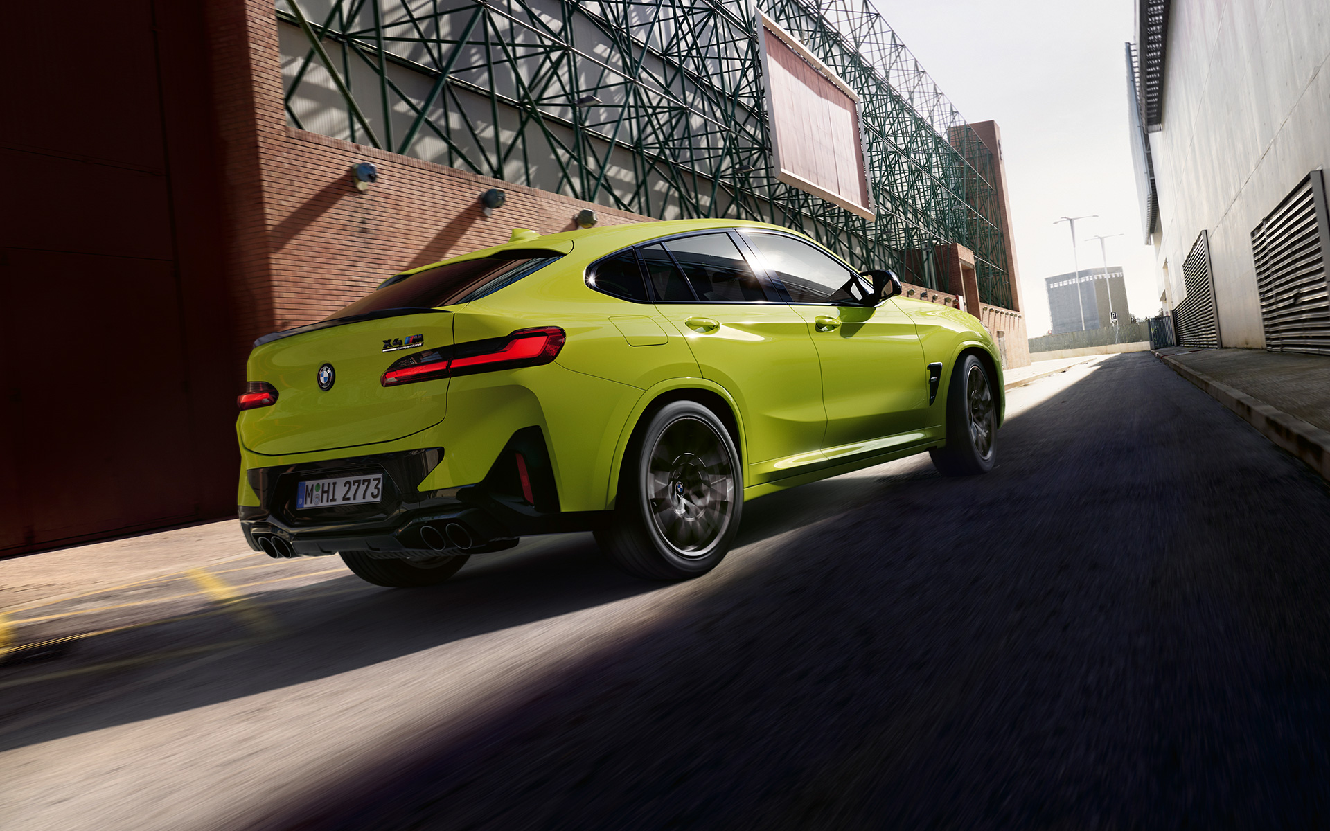 BMW X4 M Competition F98 LCI Renovación 2021 Sao Paulo Gelb Vista de tres cuartos de la zaga circulando entre naves industriales