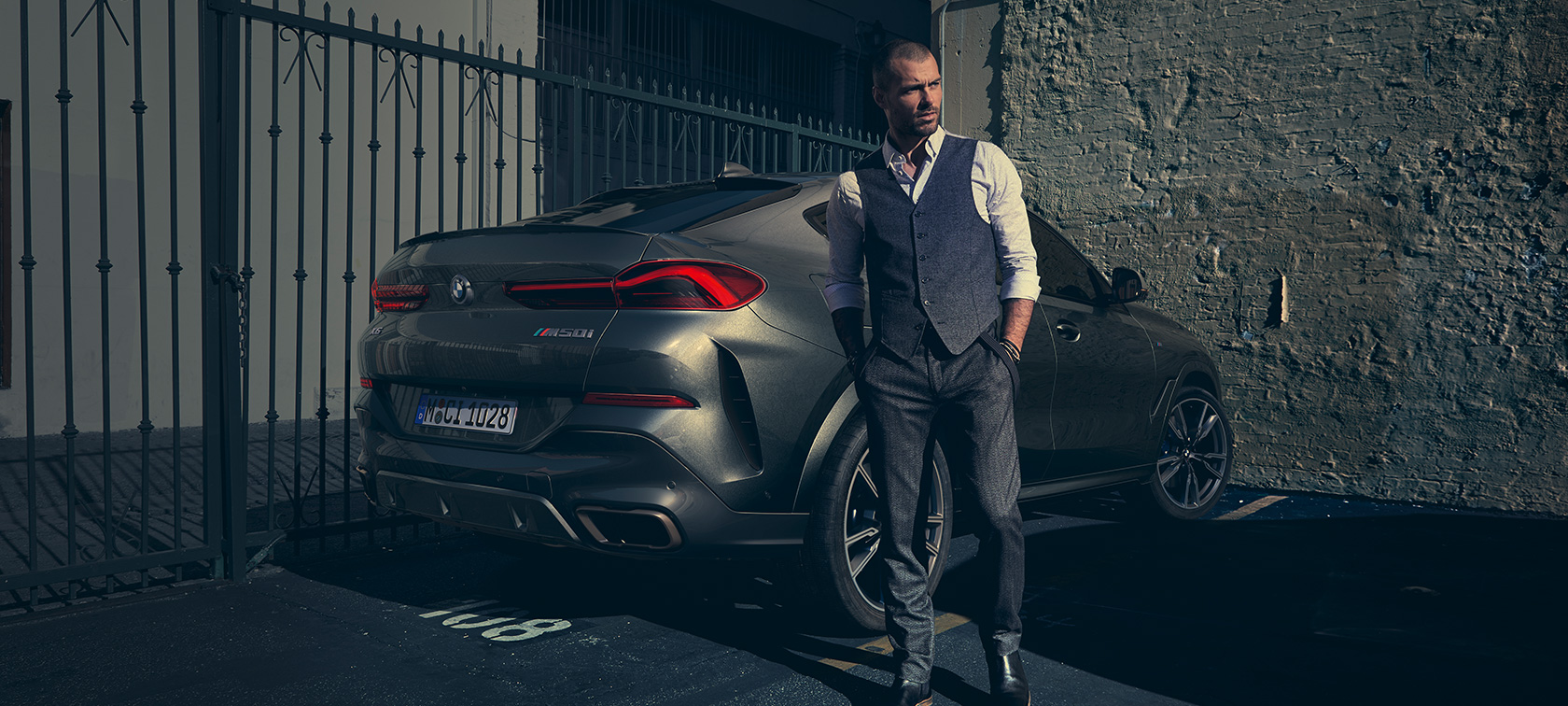 BMW X6 M50i en vista de tres cuartos de la zaga G06 Hombre parado junto al BMW X6 M50i G06 2018 SUV en vista de tres cuartos de la zaga