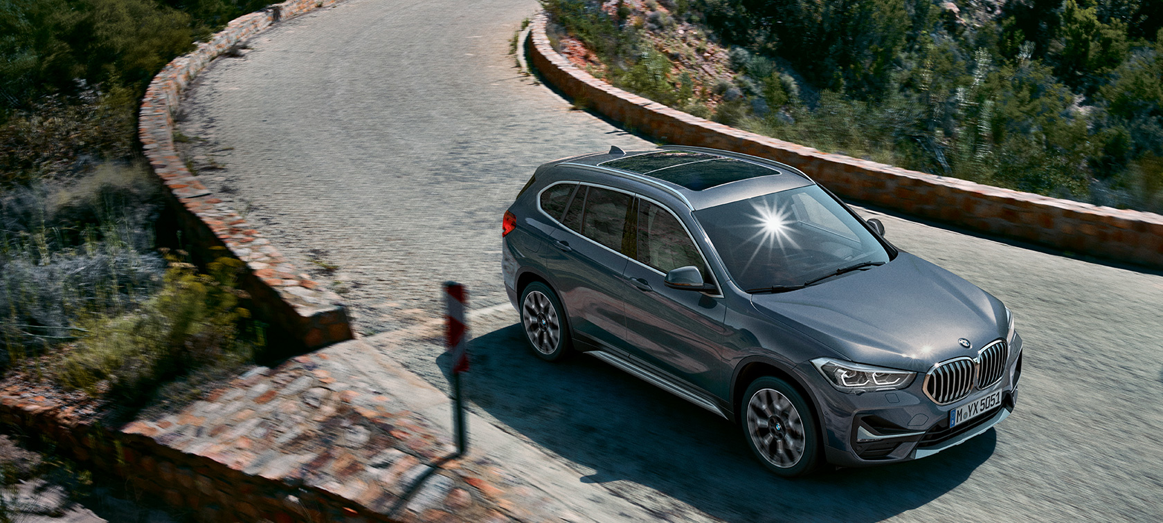 BMW X1, vista frontal tres cuartos. BMW X1, vista frontal tres cuartos frente a un escenario todo terreno.