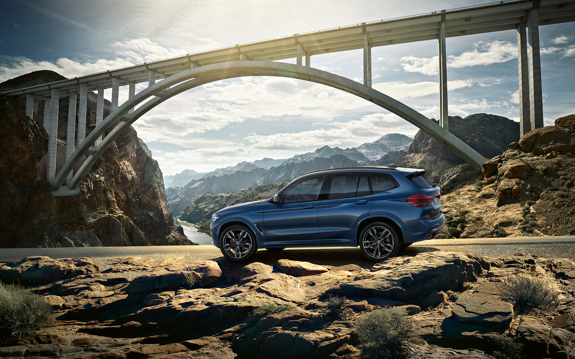 BMW X3 azul en las montañas con puente al fondo BMW X3 azul en las montañas con puente al fondo