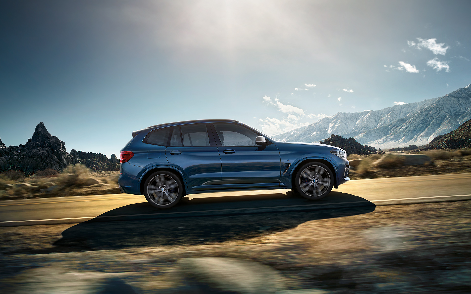 BMW X3 azul: vista lateral derecha con montaña al fondo BMW X3 azul: vista lateral derecha con montaña al fondo