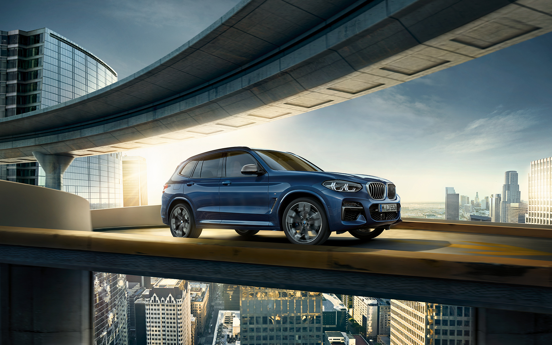 BMW X3 azul sobre un puente con ciudad al fondo BMW X3 azul sobre un puente con ciudad al fondo