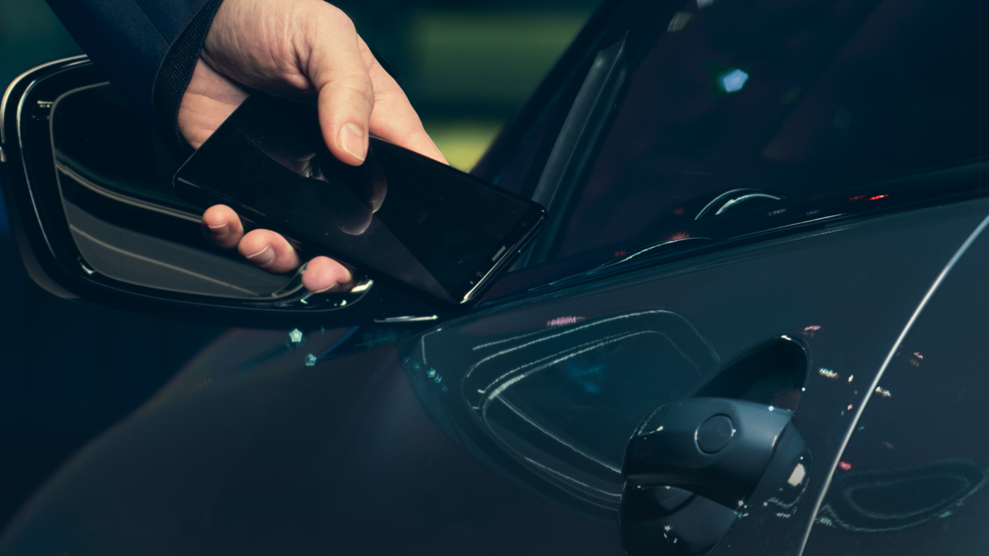 Llave digital Llave digital: Hombre sosteniendo su smartphone frente a la puerta de vehículo desde fuera