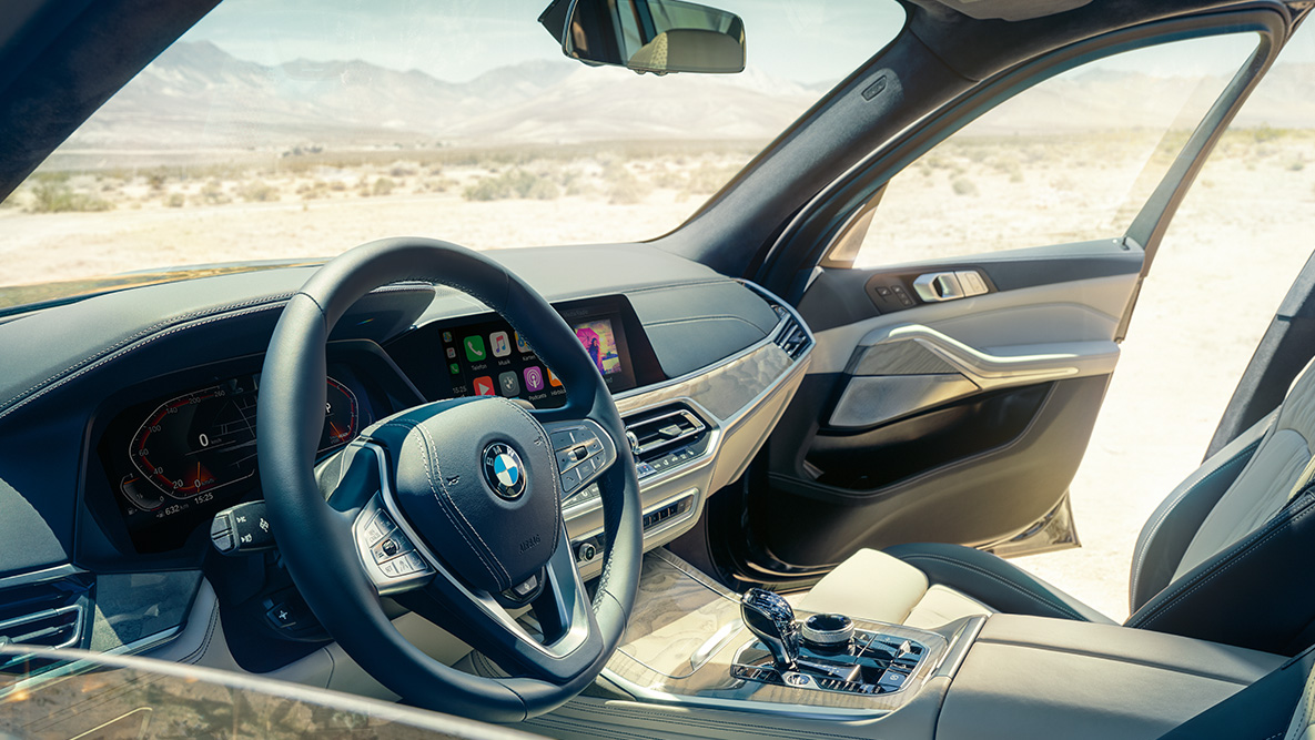 Interior del BMW X7: vista desde fuera hacia la primera fila de asientos con vista al volante, panel de instrumentos y asientos de piel BMW X7 interior