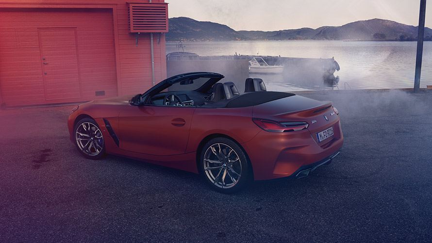 Vista trasera del BMW Z4 naranja Primera Edición Vista trasera del BMW Z4 naranja Primera edición frente a casa roja en la orilla
