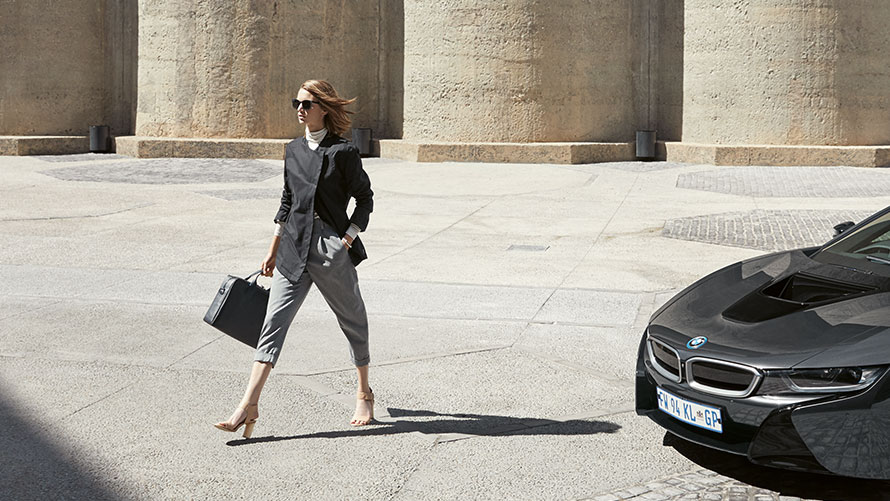 Bolsa de cuero BMW i. Se muestra una mujer llevando en la mano una bolsa de cuero BMW i de la colección BMW i.