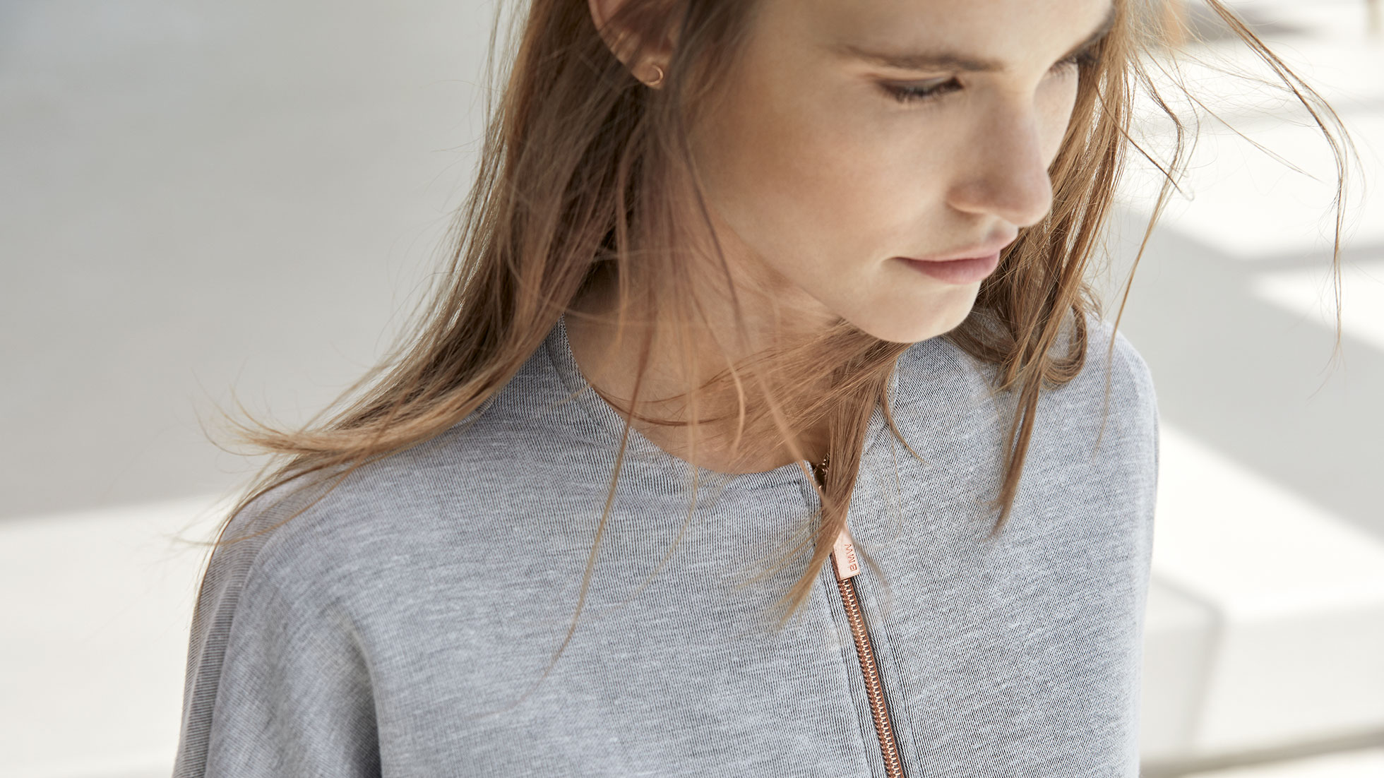 Sudadera BMW, para mujer. Se muestra a una mujer con una sudadera BMW, para mujer de la colección BMW.