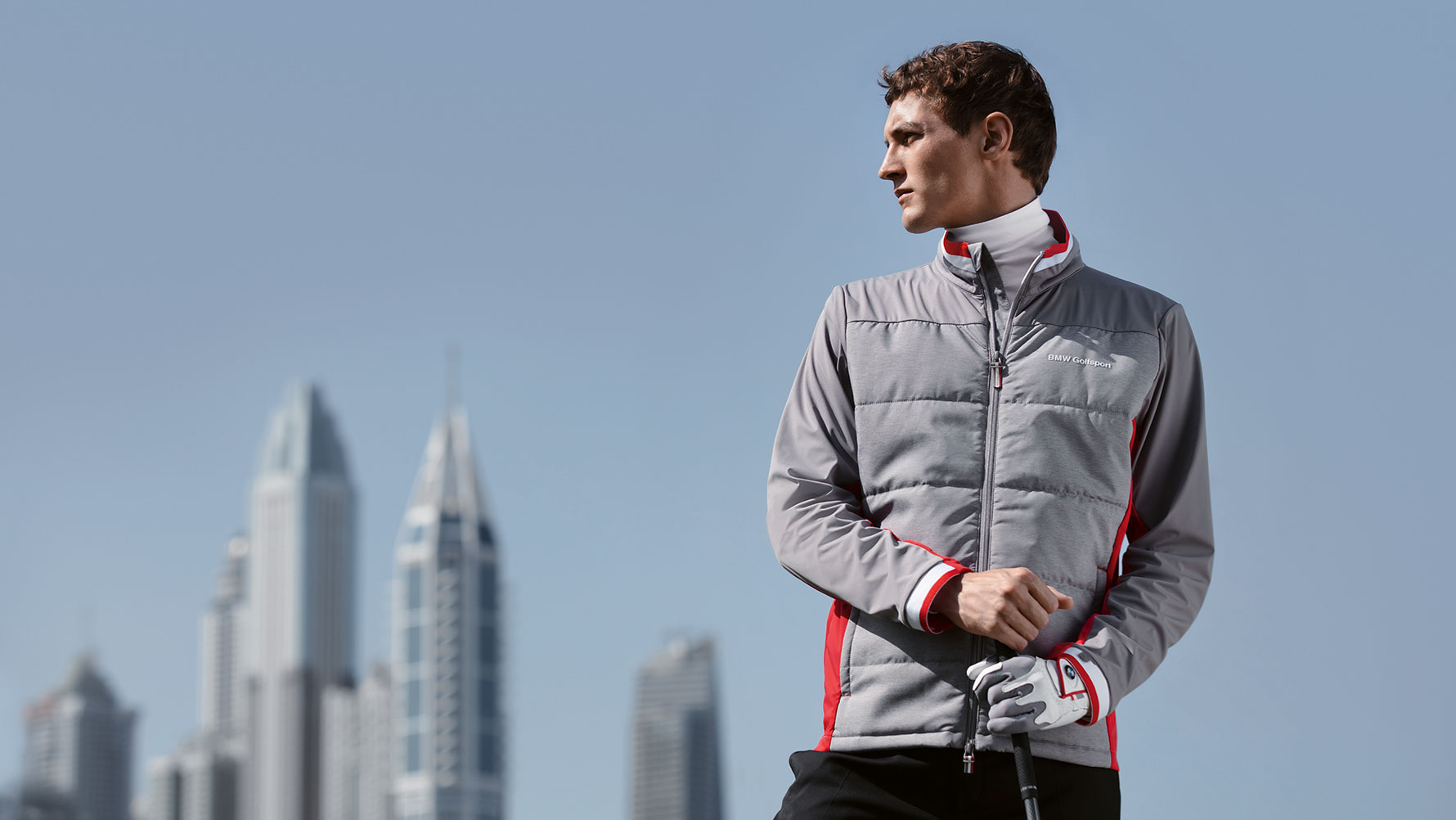 En la imagen, un hombre presenta artículos de la colección BMW Golfsport con el telón de fondo del horizonte de una gran ciudad. En la imagen, un hombre presenta artículos de la colección BMW Golfsport con el telón de fondo del horizonte de una gran ciudad.