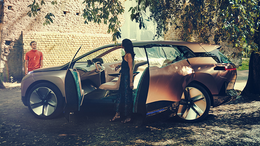 Vista lateral BMW Vision iNEXT Vista lateral del BMW Vision iNEXT con mujer en puertas abiertas y hombre en el fondo