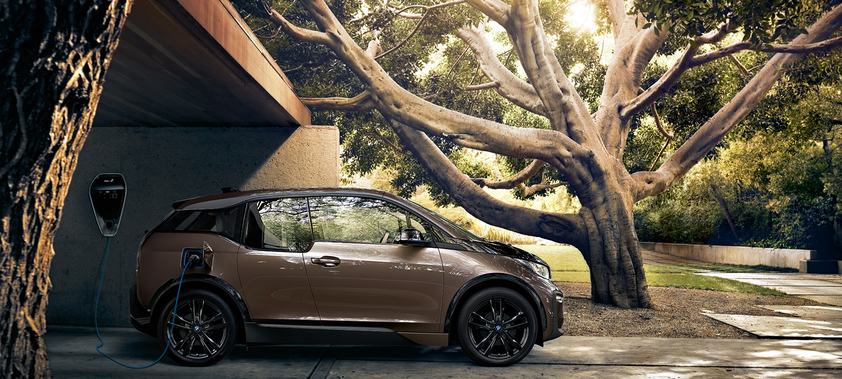 BMW i3s en su BMW i Wallbox. Vista lateral del BMW i3s en BMW i Wallbox frente a un ambiente natural.