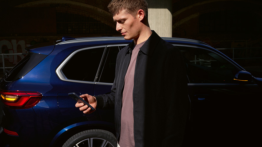 BMW Digital Key: autorizar hasta a cinco usuarios Configuración de BMW Digital Key para hasta cinco usuarios Hombre con smartphone delante de BMW X5