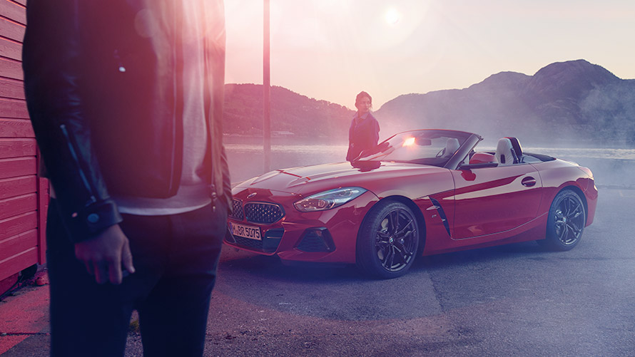 Vista de tres cuartos del frontal de un BMW ante el paisaje de montaña con mujer BMW Financial Services Seguro de motor BMW Vista de tres cuartos del frontal de un BMW delante de un paisaje de montaña con mujer