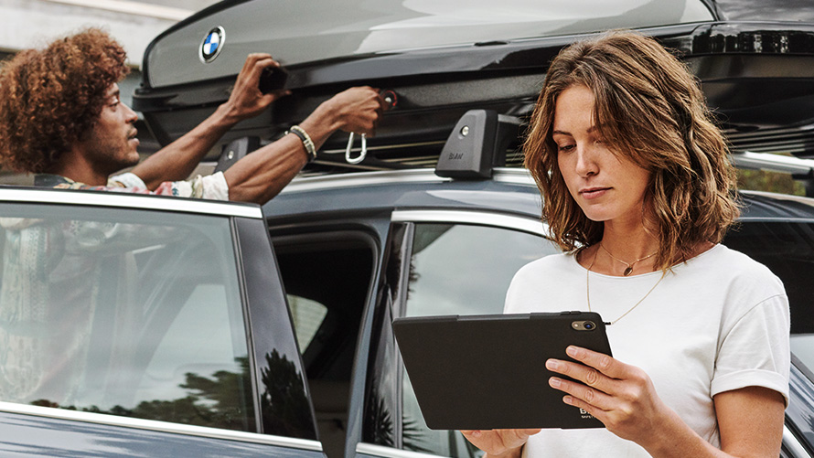 BMW Financial Services Mujer con una tablet delante de un BMW