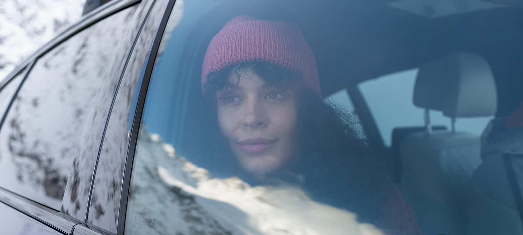 Mujer mirando por la ventanilla de un BMW Accesorios BMW para otoño e invierno, mujer mirando por la ventanilla de un BMW